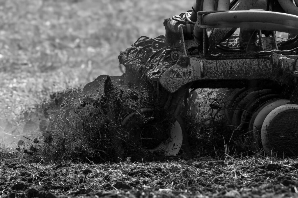 Black and white photo of machinery tilling soil, showcasing agriculture technology.
